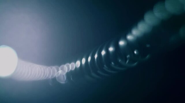The twisted wire of an old rotary telephone vibrates during conversation and shines in the dark. Closeup. Macro. Shallow depth of field