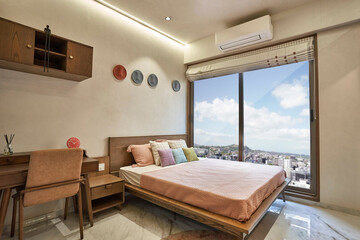 Modern bedroom with a stylish bed, wooden furniture, and city view in a contemporary apartment during daylight