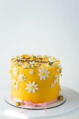 Birthday spring cake with yellow chocolate frosting decorated with edible sugar paste bees and...