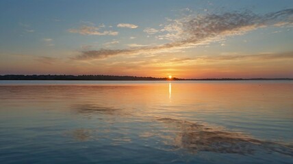 A serene sunset over calm waters at the lakeside, reflecting vibrant colors on a peaceful evening in nature. The sun dips below the horizon, casting warm hues across the sky and water