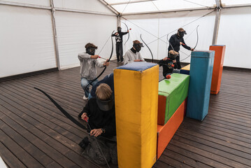 Fototapeta premium Team game of archery. Man with a crossbow arrows bow. Archer has a target, sniper. Archery challenge indoor. Archery tag Games.