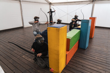Team game of archery. Man with a crossbow arrows bow. Archer has a target, sniper. Archery challenge indoor. Archery tag Games.