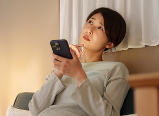 夜スマホを使う考える女性
