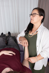 Obraz premium Woman psychotherapist with glasses performing acupressure on a patient. Concept of pna, therapy, psychotherapy, kinesiology and acupressure