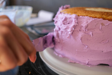 Pink cake being decorated with frosting