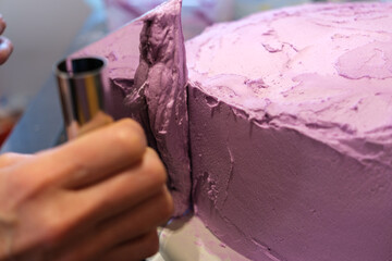 Pink cake being decorated with frosting