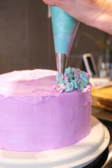 Pink cake being decorated with frosting