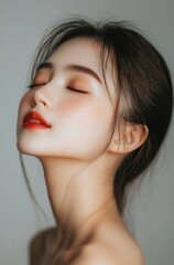 Fototapeta premium an Asian woman with her eyes closed, featuring clear and flawless skin on the front half of her face. She has delicate features and is wearing light makeup