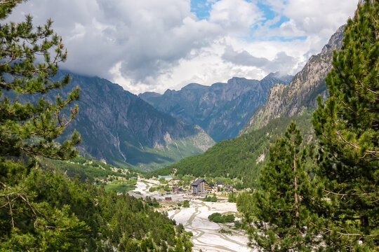 Aerial view of remote village Valbona surrounded by majestic mountain massif Kolata, Albanian Alps (Accursed Mountains), Valbone Valley National Park, Northern Albania. Luxury alpine resort hotels