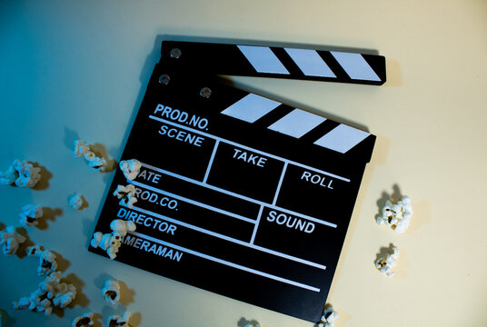 top view of popcorn on black wooden clapperboard, cinema and popcorn concept