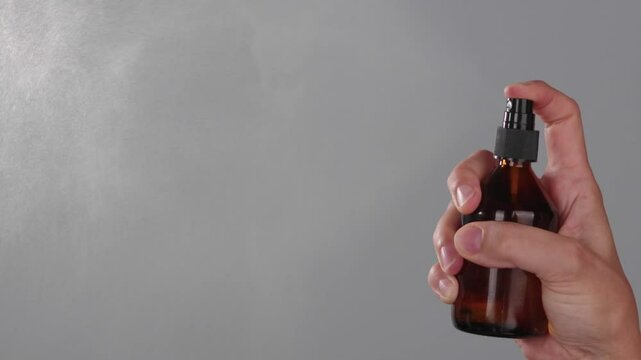 Super slow motion close-up a woman spreads antiseptic agent with her hand. Hygiene health care. Adverts for cosmetic products and self care. Spray defence to kill bacteria and viruses. Grey background