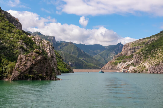 Scenic ferry boat tour on Lake Koman reservoir on Drin river surrounded by forested steep hills, cliffs and majestic rugged mountain ranges of Albanian Alps. Panoramic view along Albanian Fjords. Awe