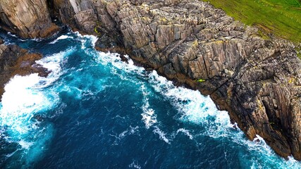 Stunning Aerial View of Vibrant Turquoise Waves Elegantly Crashing Against Rocky Shoreline