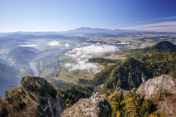 Beautiful mountain landscape. View from the Trzy Korony peak. The Tatra Mountains in the distance. The Dunajec River Valley. Autumn landscape. Clouds below the peaks. A winding river. Sromowce Niżne,