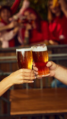 Dynamic toast among sport fans, glasses brimming with beer. Background blur emphasizes shared excitement. Concept of Oktoberfest, brewery, vacation, Friday mood. Selective focus.