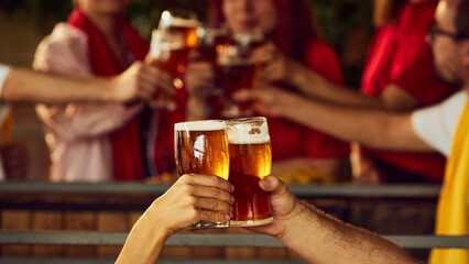 Toast to victory. Fans celebrate with their beers, blurred crowd behind them buzzing with shared emotion and energy. Concept of Oktoberfest, brewery, vacation, Friday mood.
