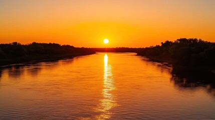 Naklejka premium A deep orange sunset over a calm river.