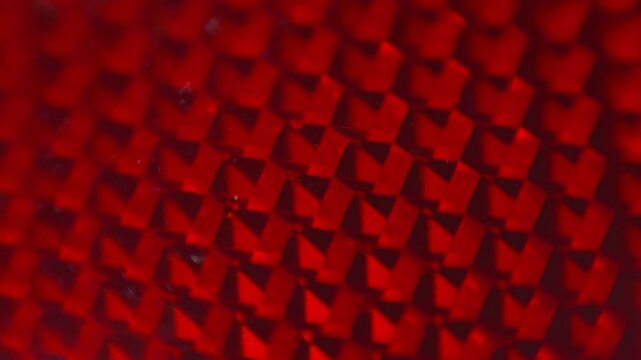 The internal structure of a red reflector, explaining the high degree of reflection of the light entering it. Closeup. Macro. Shallow depth of field. Shot in motion