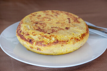 A whole classic Spanish tortilla known as tortilla de patatas, staple traditional specialty made with simple ingredients like potatoes, onions and eggs, served as tapa, side dish, even as main course