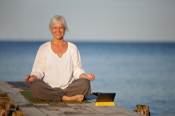 Mature woman, portrait and meditation with tablet by lake for online tutorial, lesson or virtual...