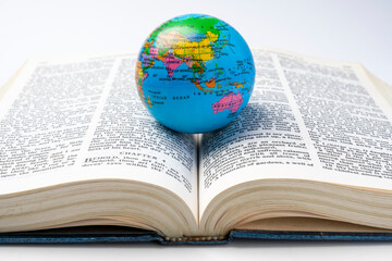 Opened book of Holy Bible with globe. It is laying on white background. Symbol of faith and worship...