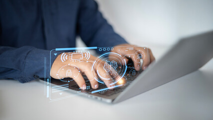 A man is typing on a laptop with a blue shirt on