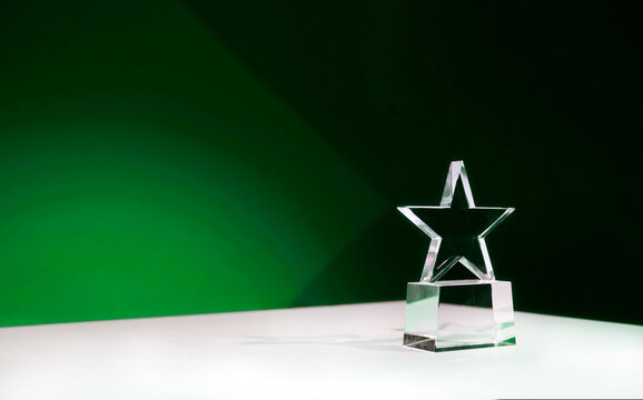 Sustainability award - star-shaped crystal prize on a table with green spotlights and copy space