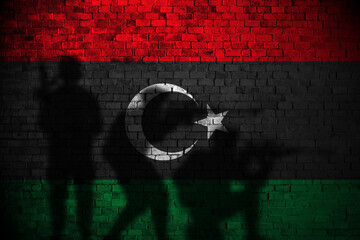 libya flag on brick wall and soldiers shadow