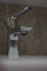 A drop flows out of an open tap, breakage
