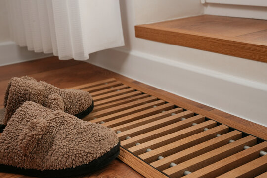 Contemporary water underfloor heat convector installed near panoramic window with fluffy slippers.  In-floor convector. Energy consumption in cold season. Concept of smart home. Side view.