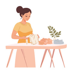 A pregnant woman folding baby clothes at a table