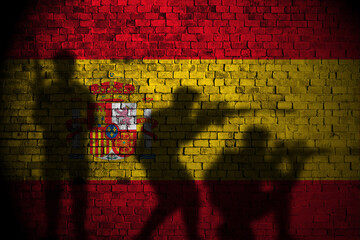 spain flag on brick wall and soldiers shadow