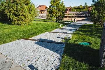 Fototapeta premium A peaceful and serene pathway winds through a beautiful green park, featuring a charming cobblestone walkway and lush, inviting grass