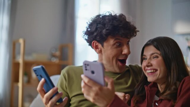 Amazed winners watching smartphones reacting success at room together closeup