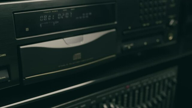 Male hand taking compact disc from CD player and closing tray in hi-fi music center. Closeup. Macro. Shallow depth of field. Shot in motion