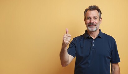 Mature man with confident smile giving thumbs up against yellow background with copy space