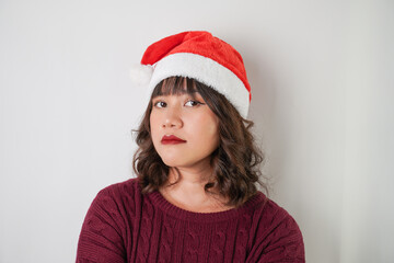 Excited young asian woman wearing santa clause hat and red long sleeved sweater with smiling face expression, isolated over white background. Concept for Christmas Holiday and New Year Party