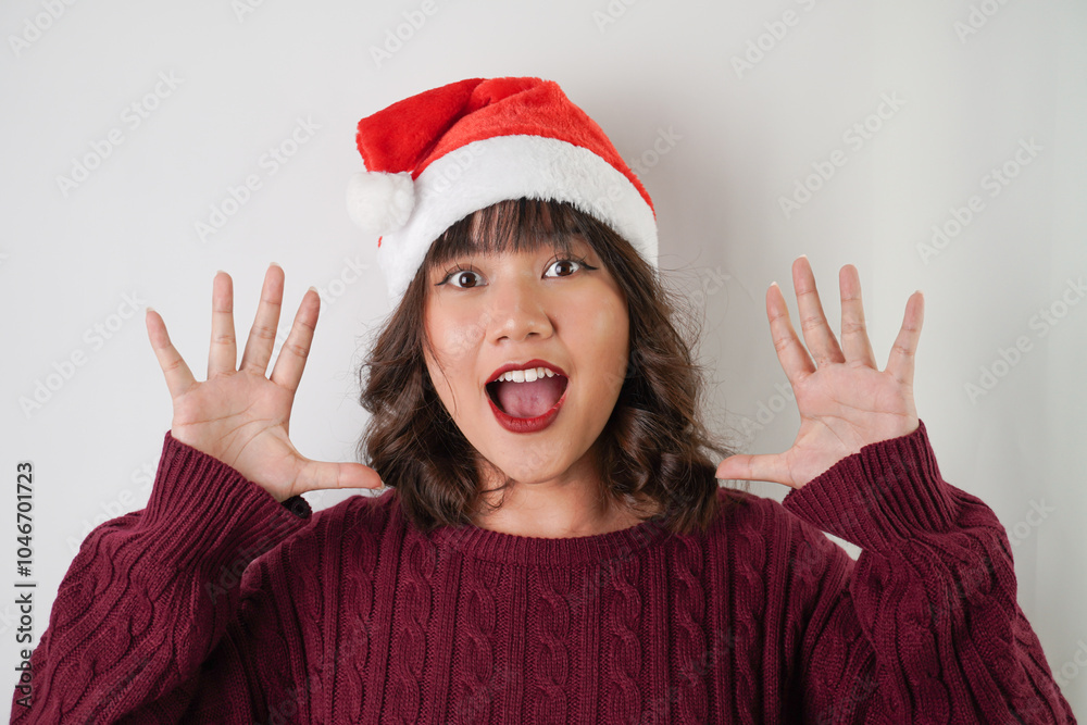 Wall mural excited young asian woman wearing santa clause hat and red long sleeved sweater with smiling face ex