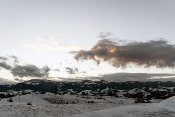 Snowy mountain landscape with dramatic clouds and soft evening light at sunset