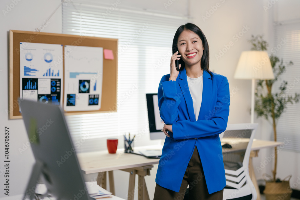 Poster asian businesswoman is smiling while having a conversation on her phone in a modern office with char