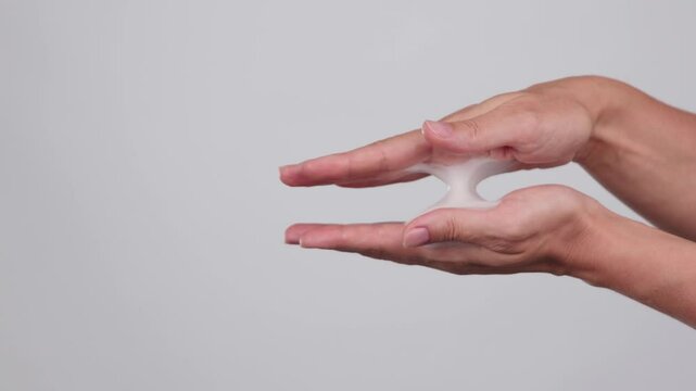 Slow motion close-up young women hands, soap foam, face foam bubble, baby soap, body hygiene. Product concept, skin care ads. Femme squeezing white lather on a grey background. Commercial Slow motion