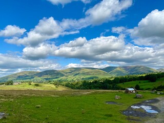 Rolling Hills and Green Fields Under a Blue Sky with Clouds