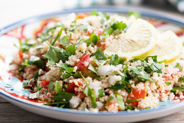 Tabbouleh salad with couscous on wooden table. Close up