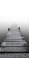 Fototapeta premium Wooden pier stretches into the fog above calm water evoking solitude and serenity in a minimalist setting