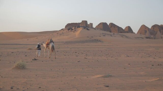 Sudan, Meroe, man and camel in front of pyramids and tombs in royal cemetery