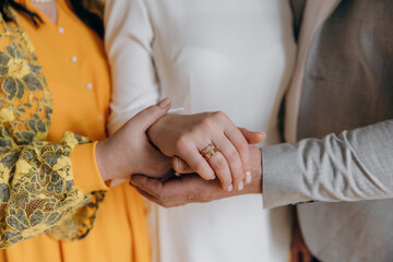 Obraz premium Parents hold their daughter's hand on their wedding day. A girl's wedding with the support of her parents. Golden wedding ring