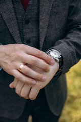 Fototapeta premium A stylish businessman in a suit and tie holds a watch on his hand. A man watches the time