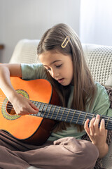 A cute girl plays the guitar. A little girl with a guitar.