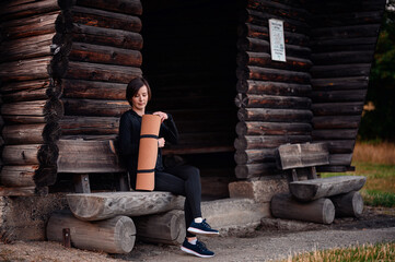 Fototapeta premium Woman relaxing with yoga mat and apple at a wooden cabin