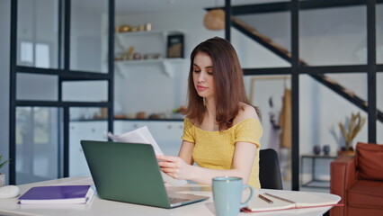 Young businesswoman reading report working remotely at laptop in home closeup.